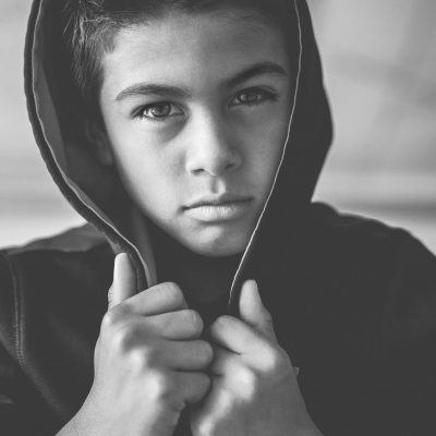young boy wearing a hoodie and staring moodily into the camera lens